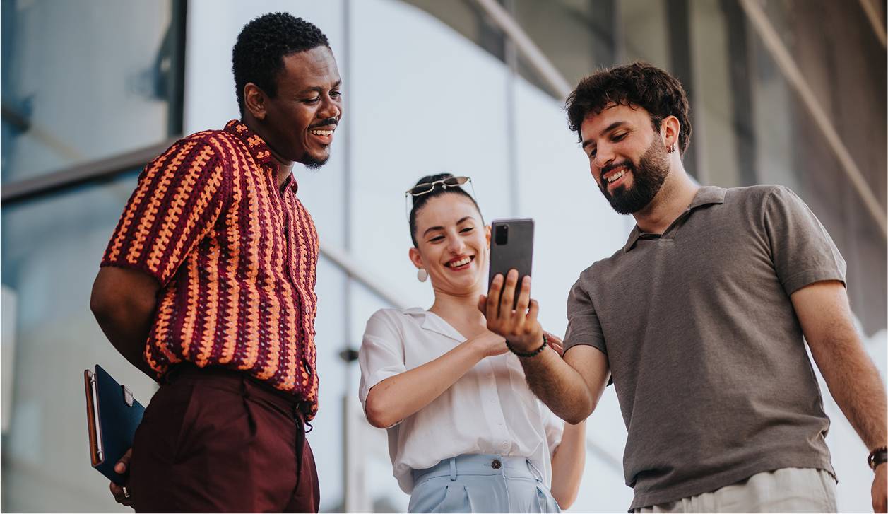 Three business people talking while looking at phone-rectangle