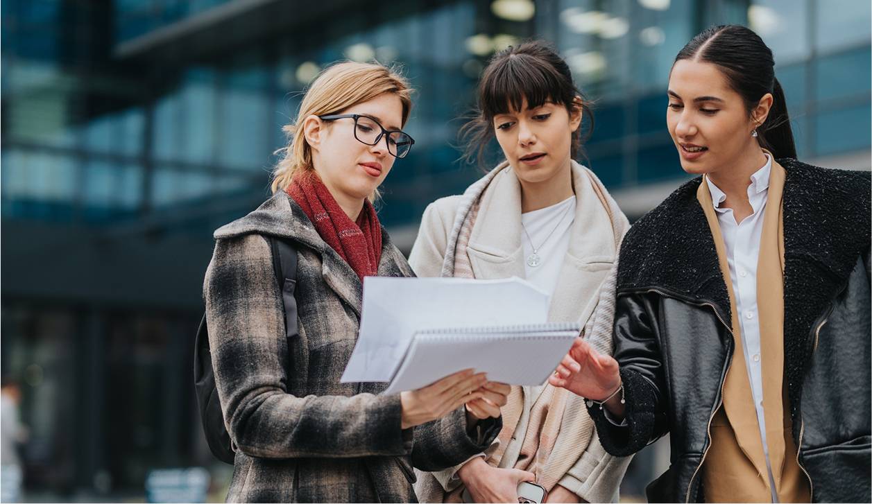 Three professional woman outside dicussing documents-rectangle