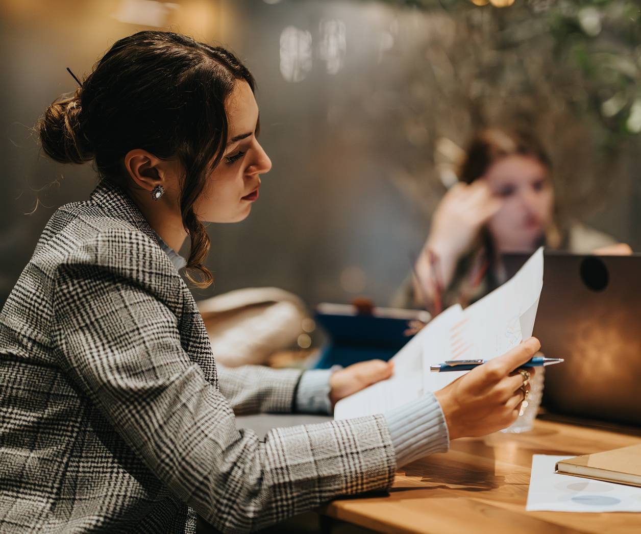 Woman in grey jacket looking at papers at night