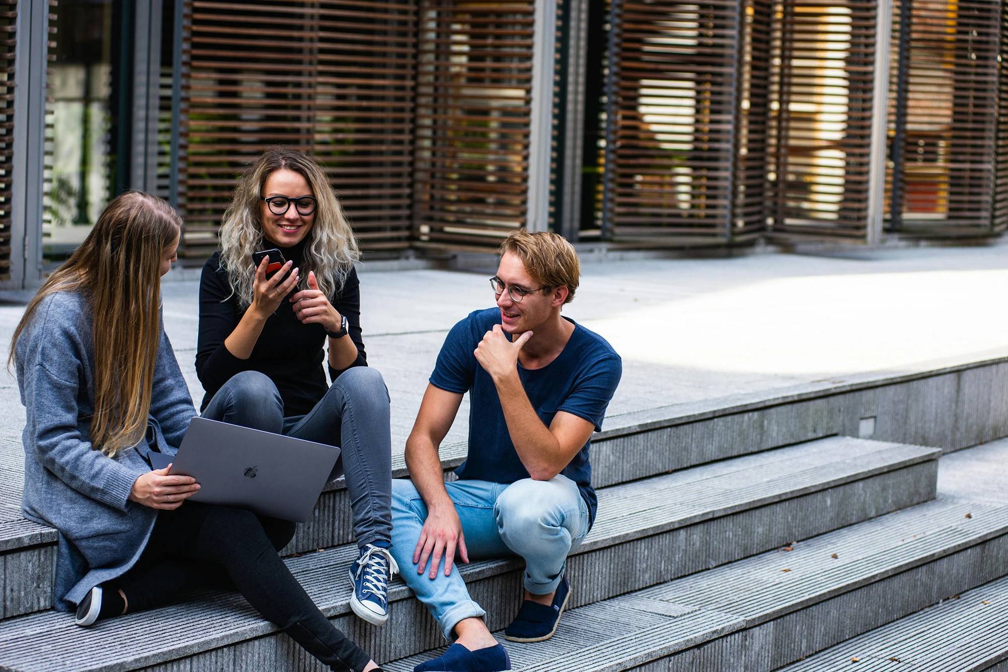 Group of people sitting on stairs with a laptop and phone